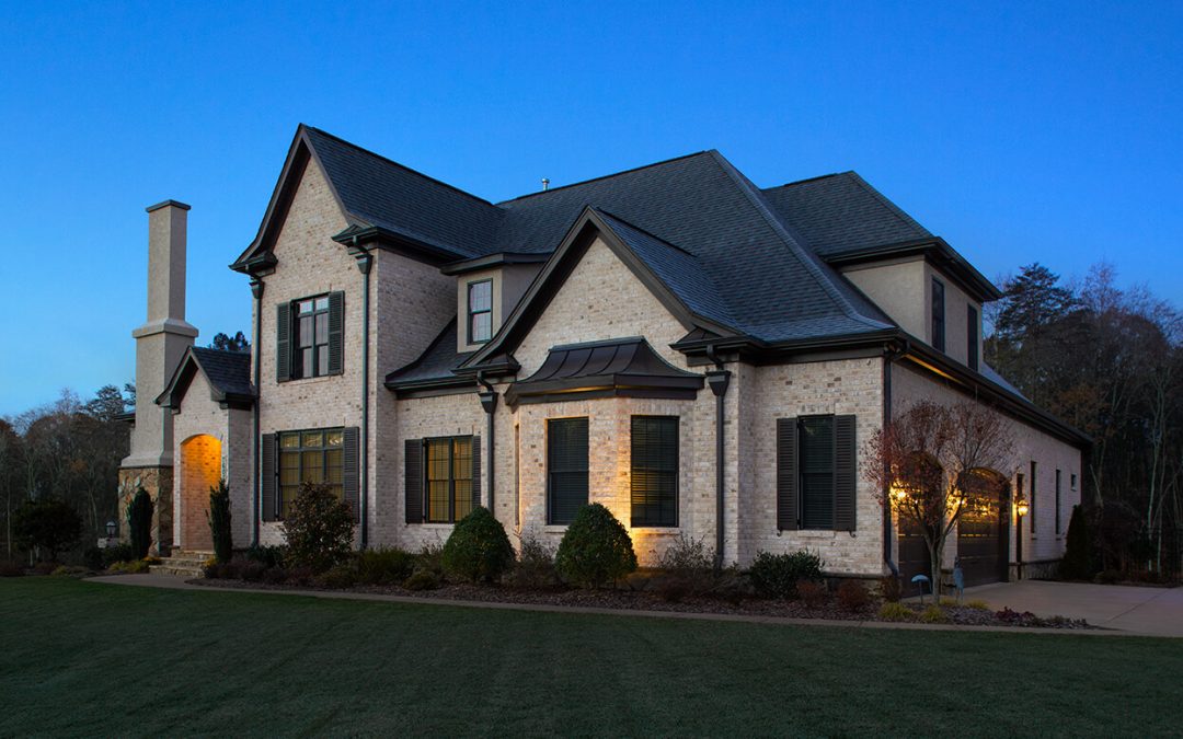 Two-story home with light tan brick from North Georgia Brick, dark roof, and shutter accents, beautifully lit at dusk.