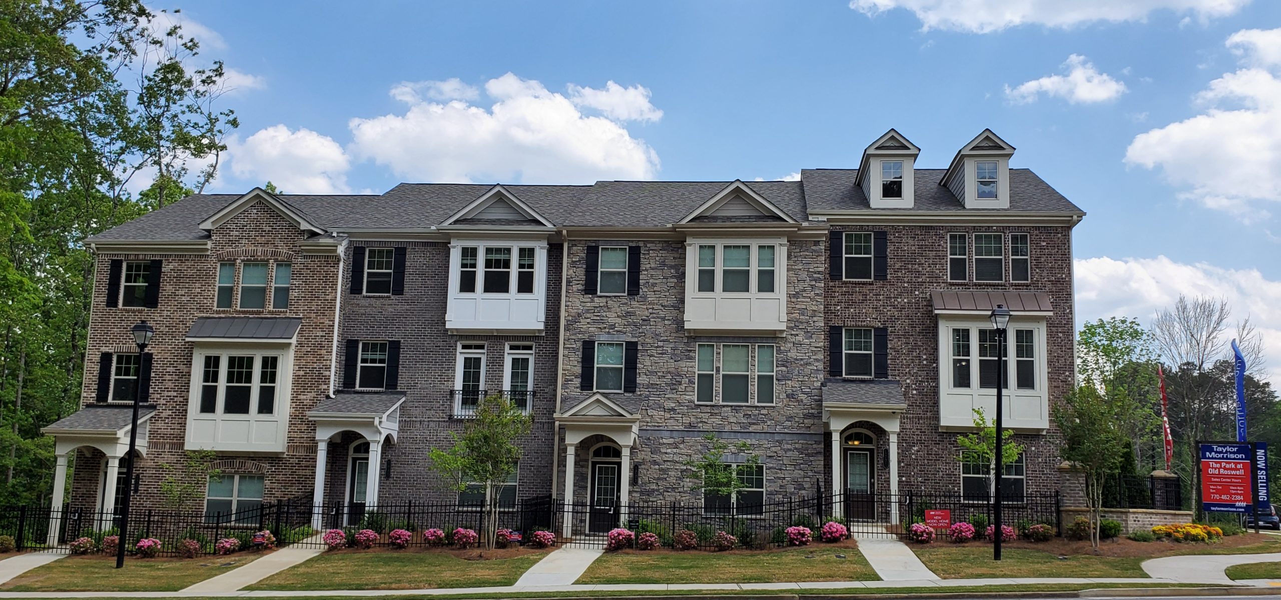 Townhome row at Taylor Morrison’s The Park at Old Roswell with several shades of brick alternating with stone.
