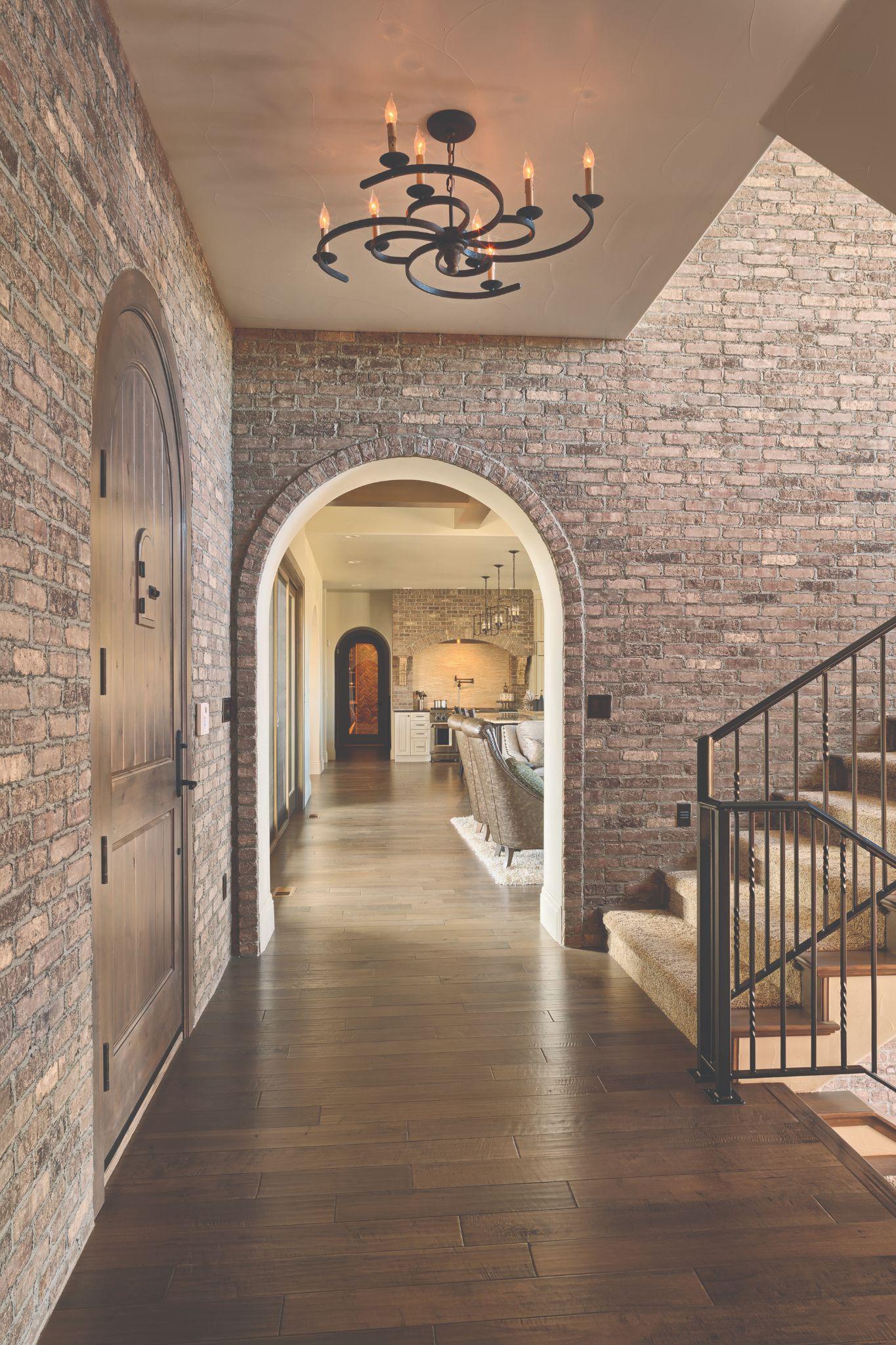 Ironworks thin brick wraps the walls and arched entryway of a home interior.